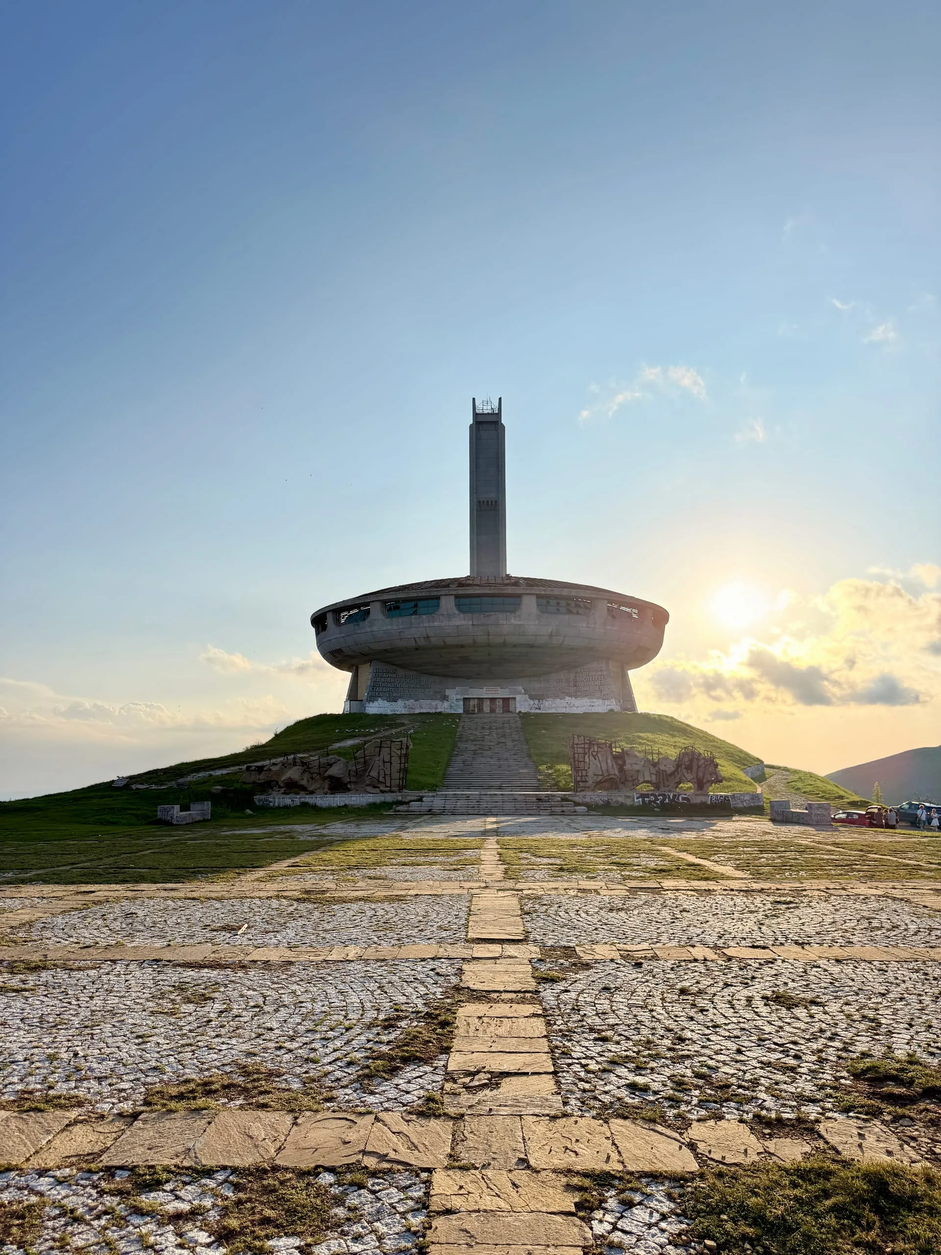 The circular concrete Buzludzha monument glowing at sunset on its mountain ridge