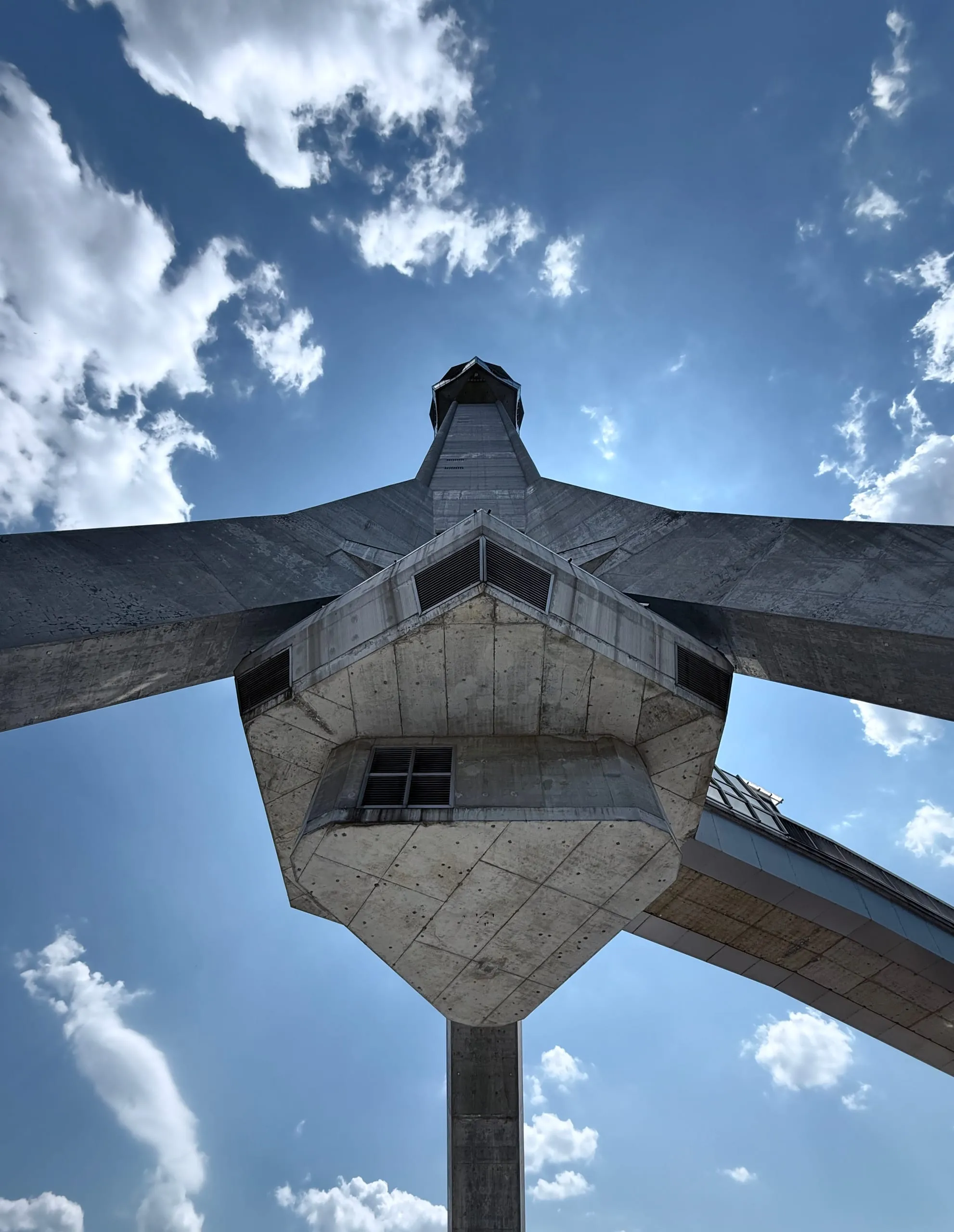 Looking straight up the three splayed concrete legs of the Avala tower to the collar where they meet