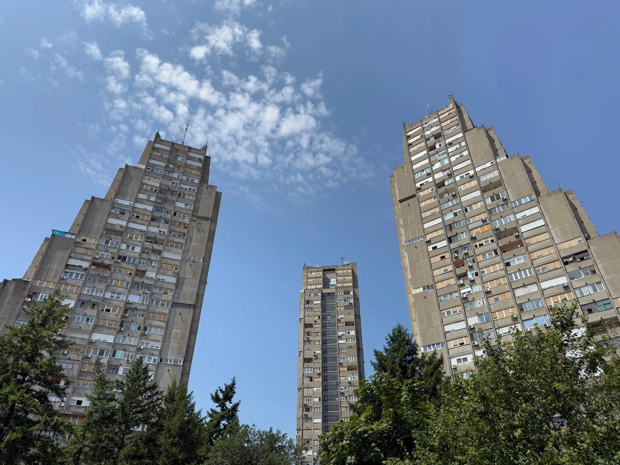 The three towers of Belgrade's Eastern City Gate seen from below against a cloud-streaked sky