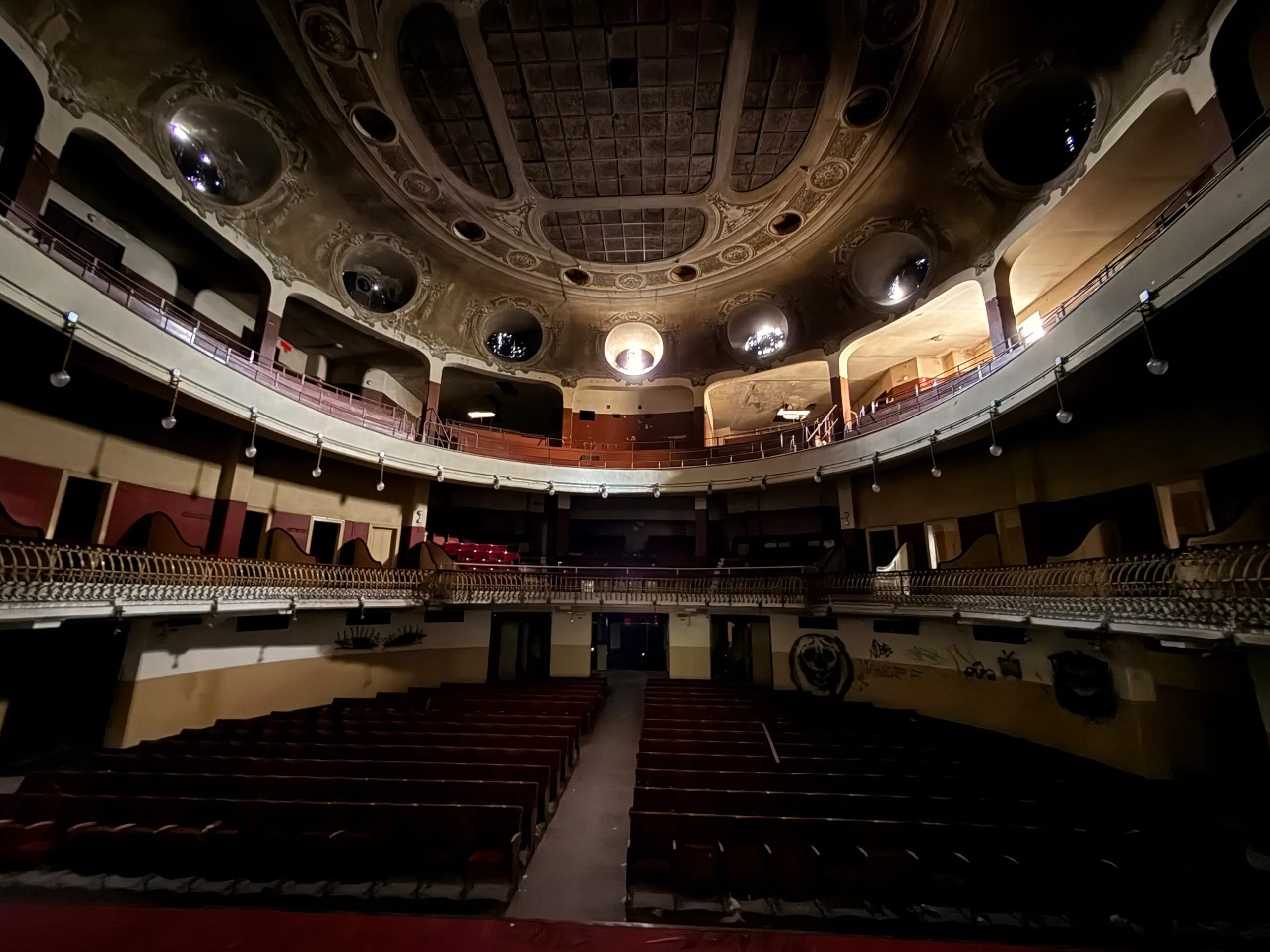 The auditorium seen from the stage — domed ceiling, two tiers of boxes, red seats still in their rows