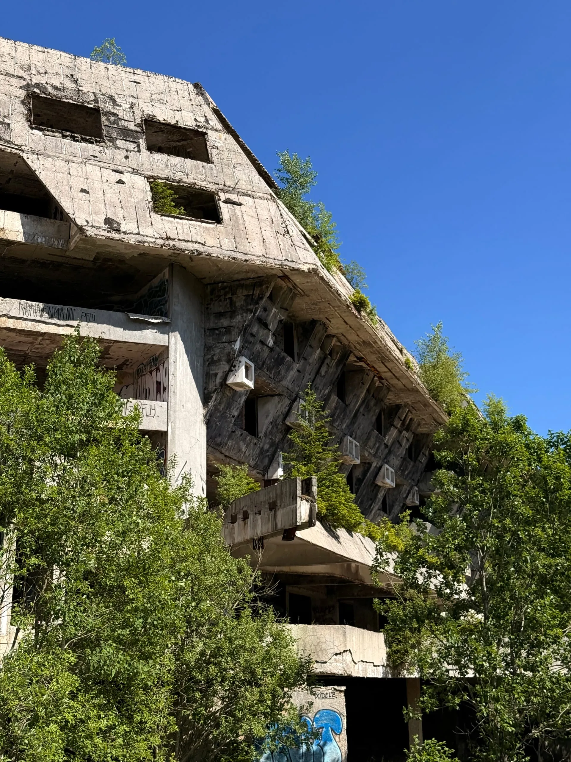 The stepped concrete facade of an abandoned modernist hotel on Mount Igman