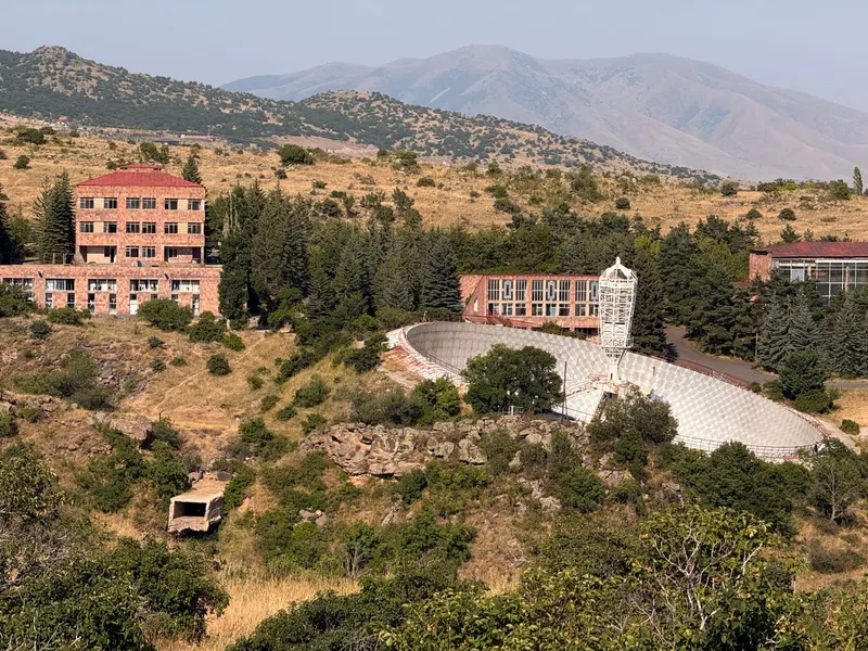 The 54-metre dish set into the hillside with its secondary tower standing in the bowl, institute buildings above it and the mountains behind