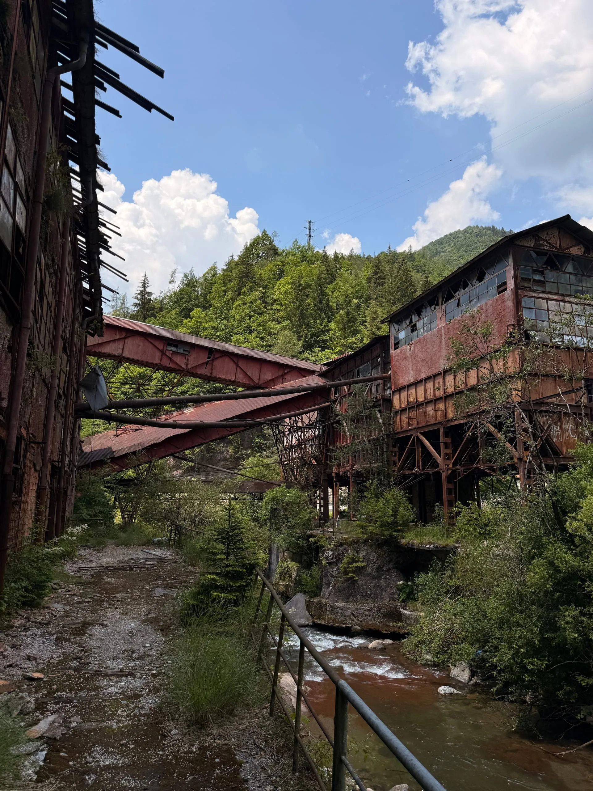 Red steel and a trestle over the torrent — the mill bridging the gorge